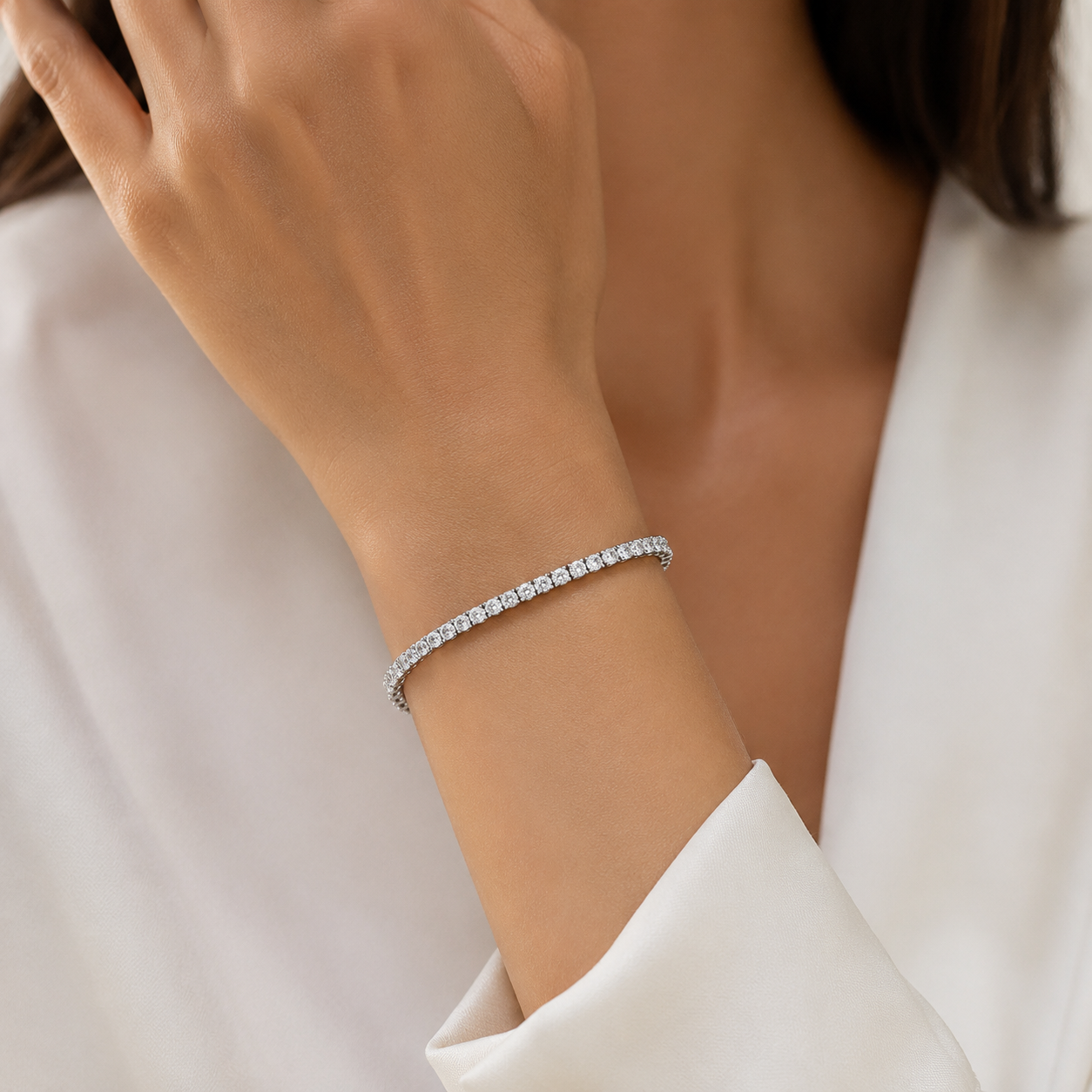 Detaliu la incheietura mainii purtand bratara liniara tennis cu finisaj premium platinat si lantisor de prelungire fin la mana unui model feminin elegant