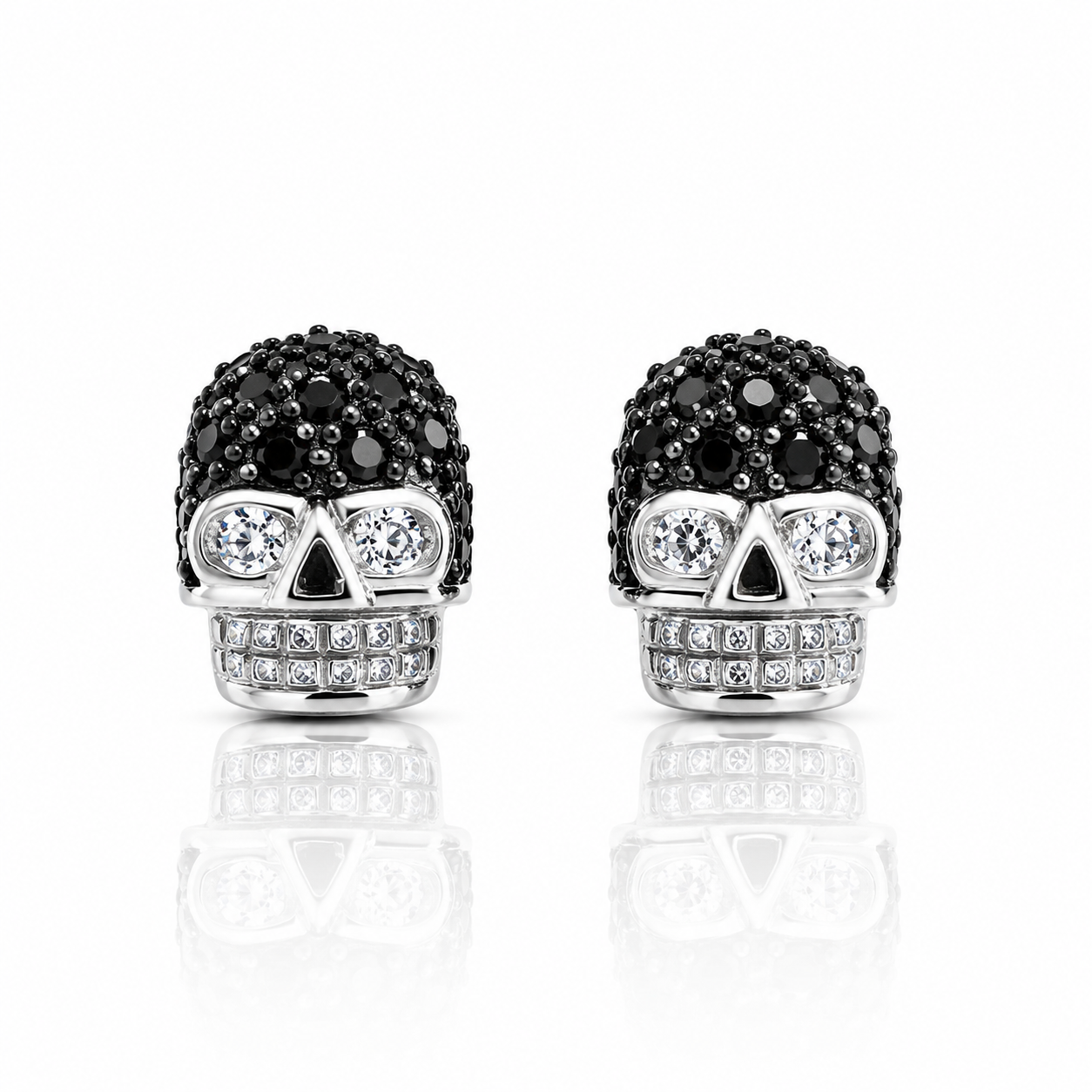 Pereche de cercei din argint 925 in forma de craniu sculptural, decorati cu un pavaj de cristale negre pe crestet si diamante cz albe pentru ochi si dinti