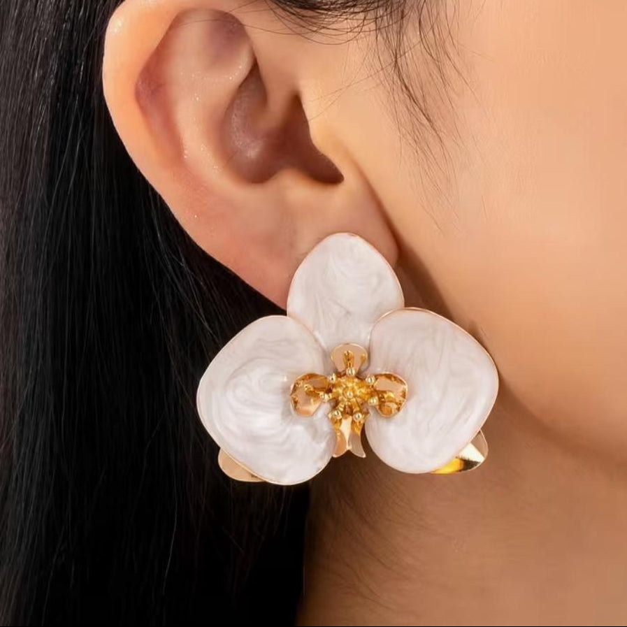 Model feminin purtand cerceii mari in forma de orhidee, punand in valoare proportiile statement de 4.7 cm si asezarea spectaculoasa pe lobul urechii