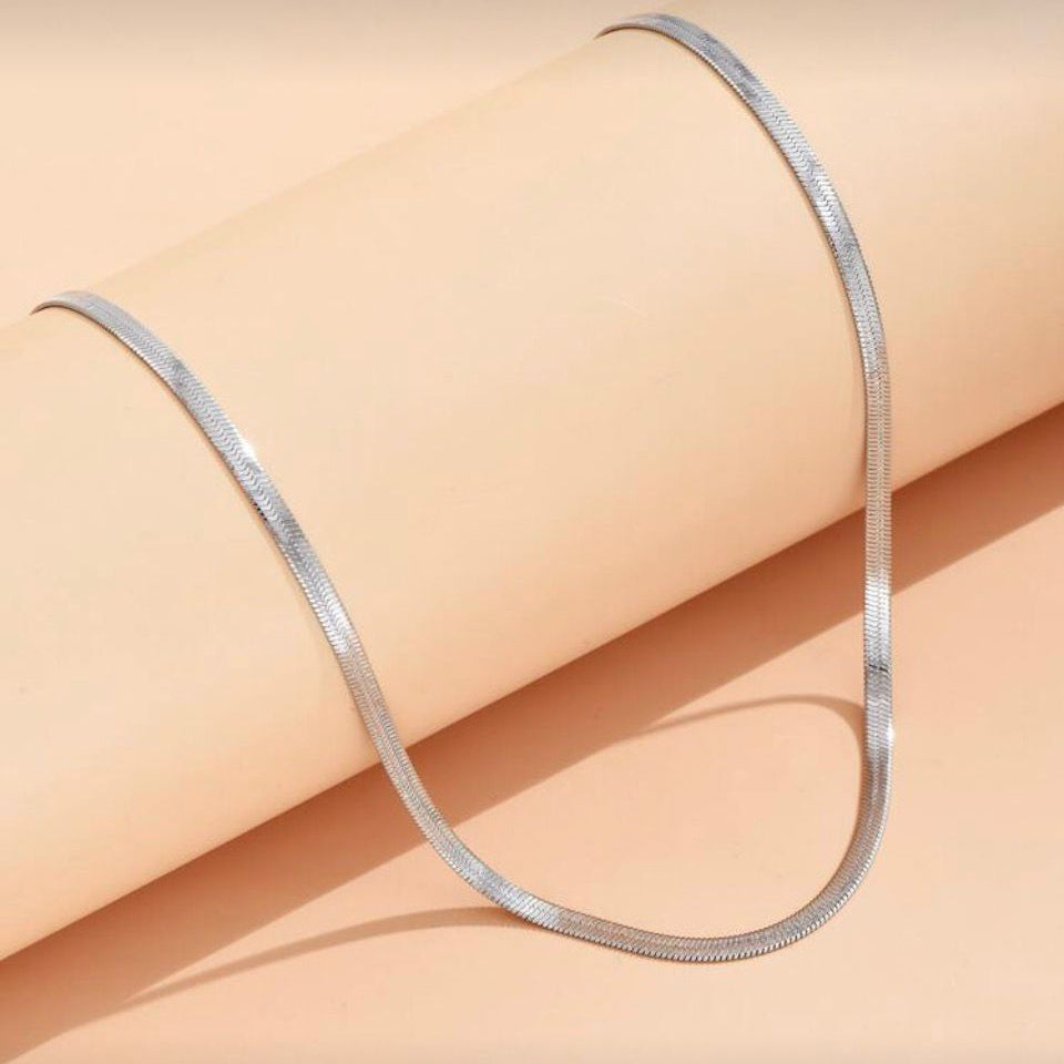 Colier de dama Herringbone lat de 3mm din otel inoxidabil placat PVD cu rodiu, expus pe fundal roz