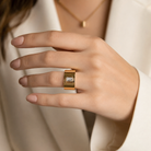 Inel lat pentru dama Trussardi realizat din otel rodiat auriu cu un diamant cz transparent dreptunghiular montat central purtat la mana unui model feminin elegant