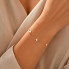 Model feminin purtand la incheietura mainii bratara fina din argint rose gold cu trei detalii in forma de inima