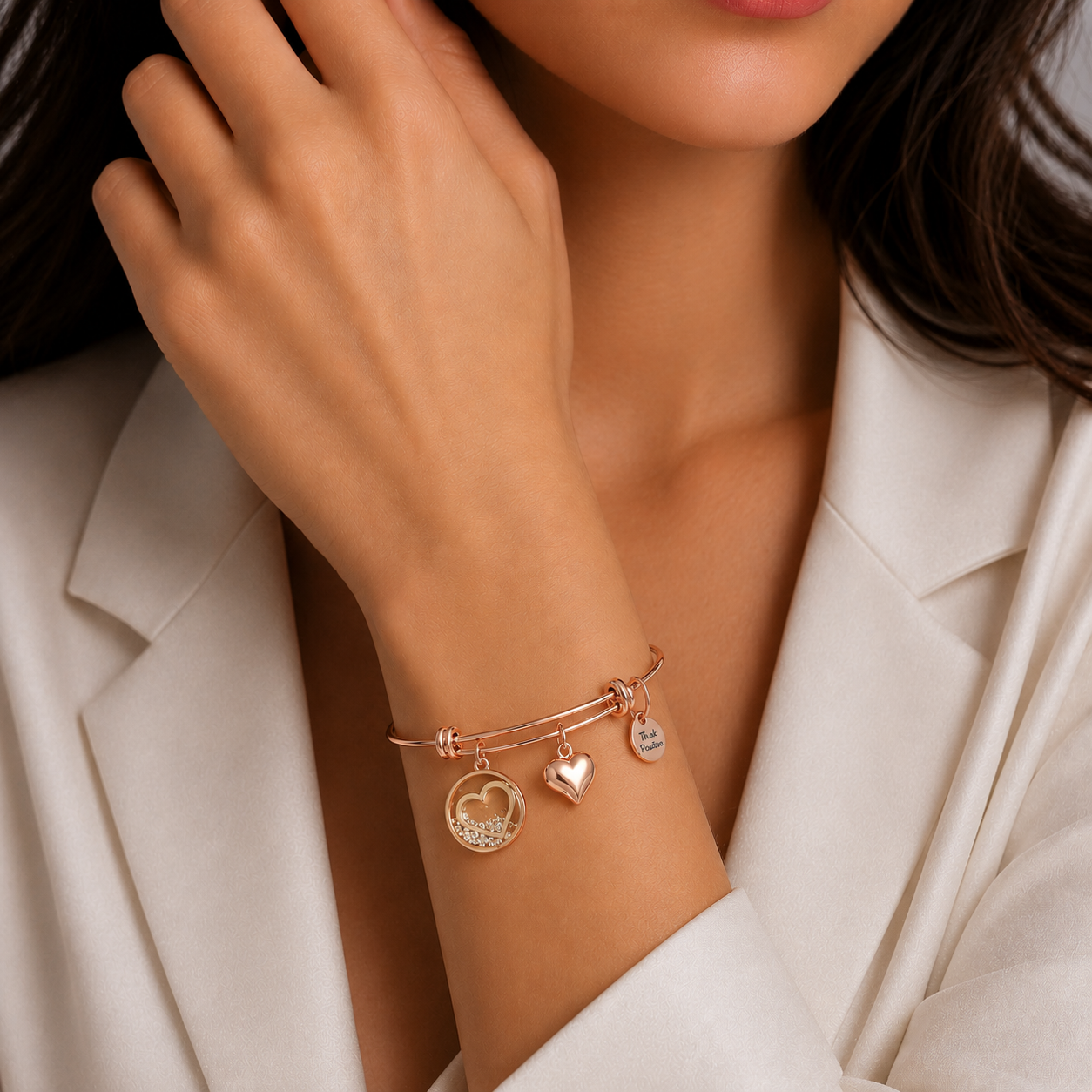 bratara rigida think positive din otel inoxidabil 316 hipoalergenic placat rose gold cu charmsuri inimi la mana unui model feminin elegant