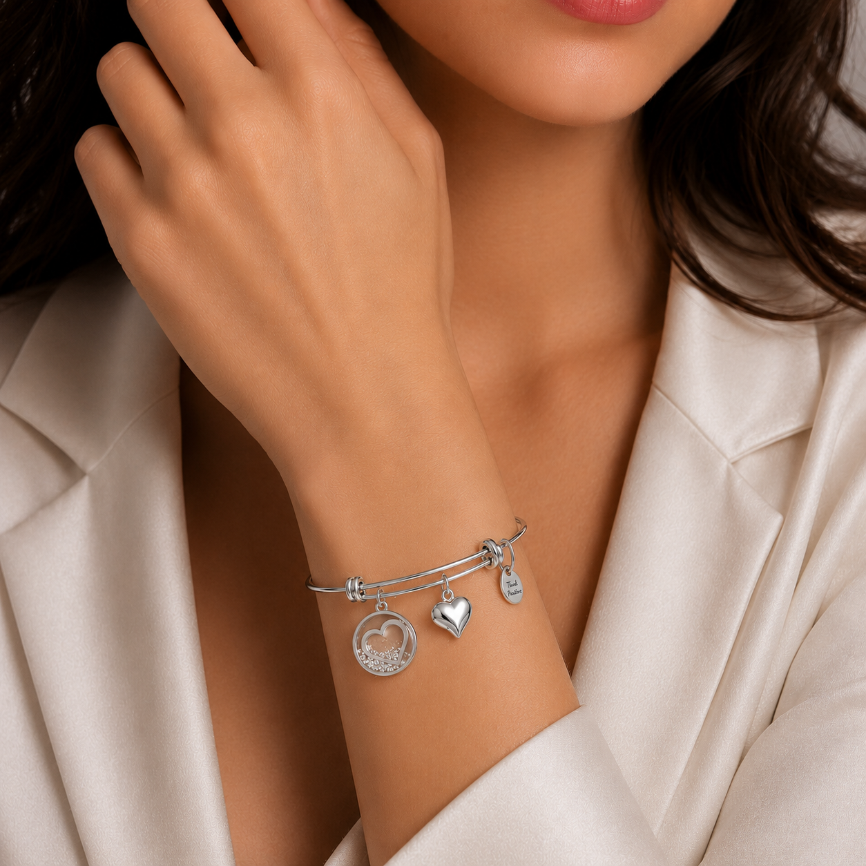 bratara rigida think positive din otel inoxidabil 316L hipoalergenic cu charmuri inimi la mana unui model feminin elegant