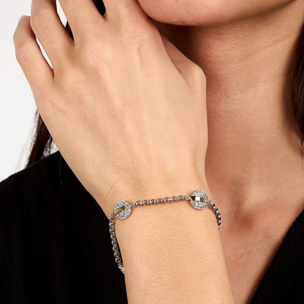 Bratara de dama Trussardi din otel inoxidabil 316L auriu si argintiu cu trei elemente rotunde decorate cu cristale albe la mana unui model feminin elegant 