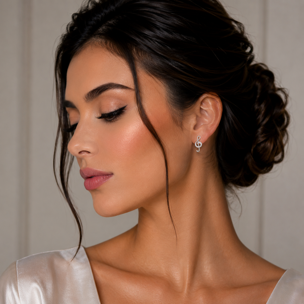 Model feminin purtand cerceii mici in forma de cheia sol din argint rodiat, evidentiind proportiile fine de 1 cm pe lobul urechii