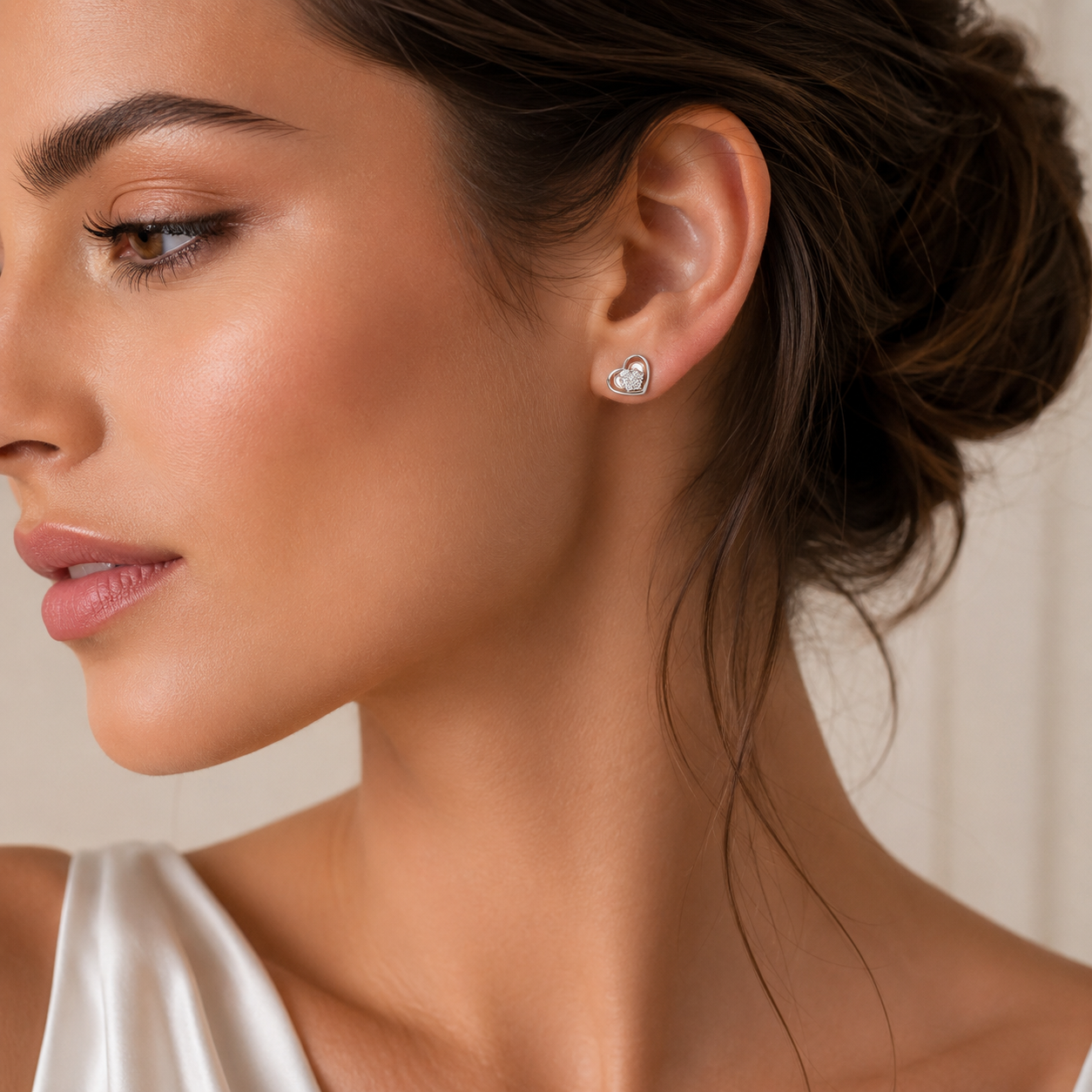 Model feminin purtand cerceii mici in forma de inima cu cluster de diamante cz din argint rodiat, punand in valoare dimensiunea delicata de 0.5 cm pe lob.