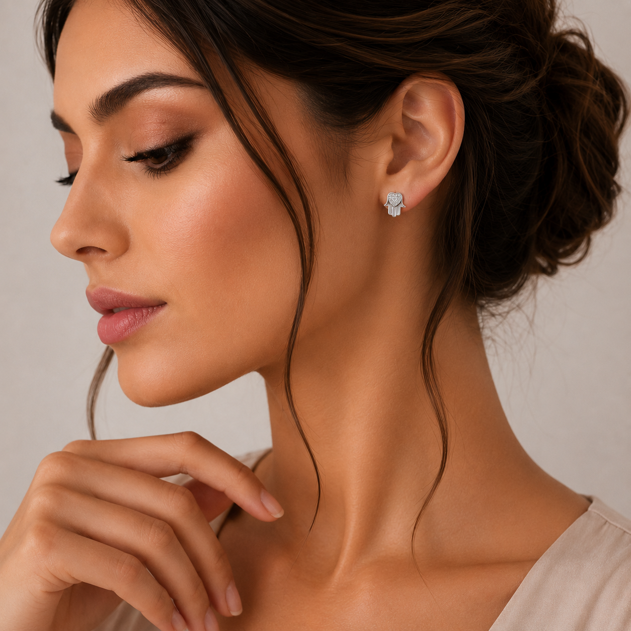 Model feminin purtand pe lobul urechii cerceii minimalisti din argint in forma de mana hamsa cu detalii stralucitoare.