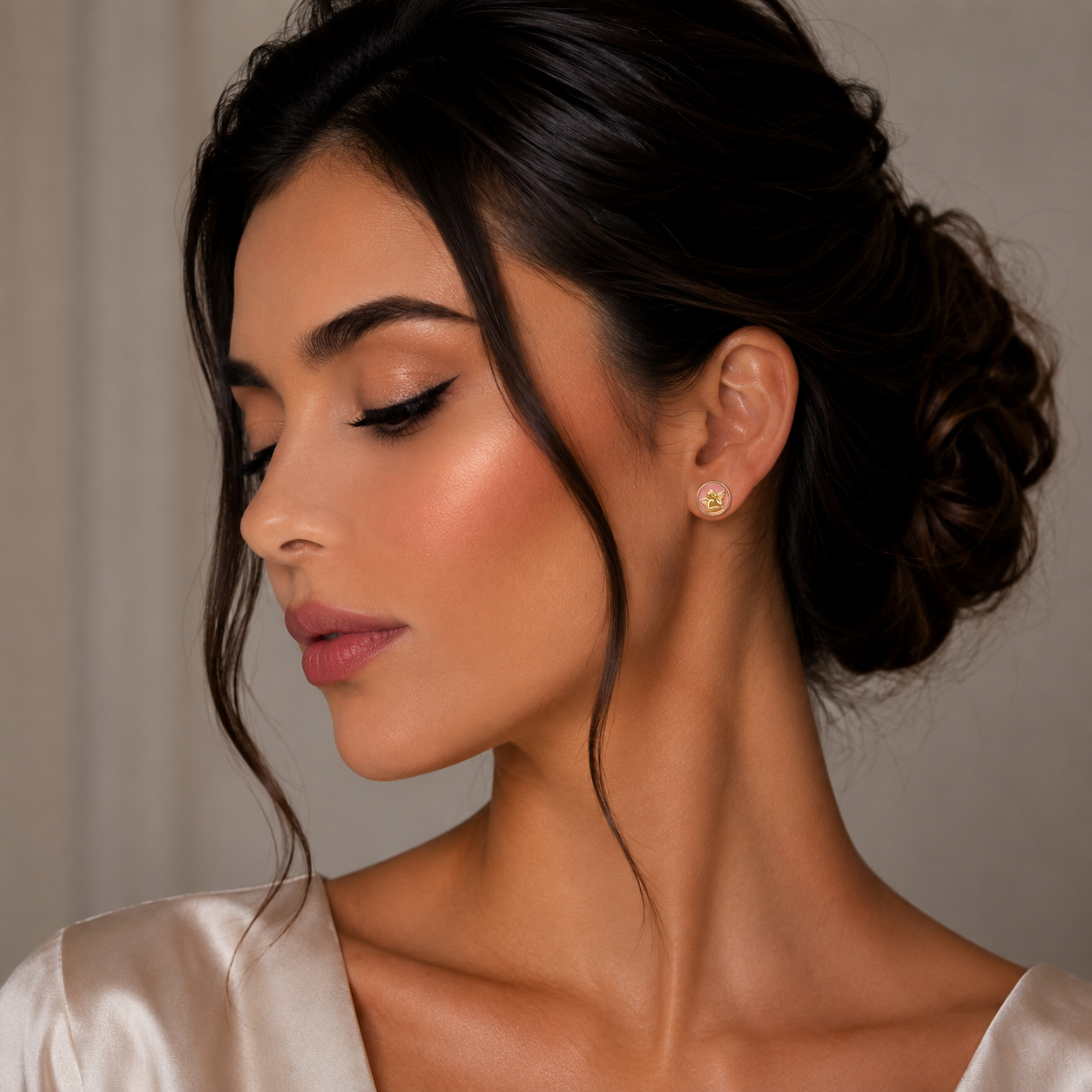 Pereche de cercei rotunzi din argint 925 rodiat rose gold, cu silueta ingeras in relief pe fundal din email roz pastel la urechea unui model feminin