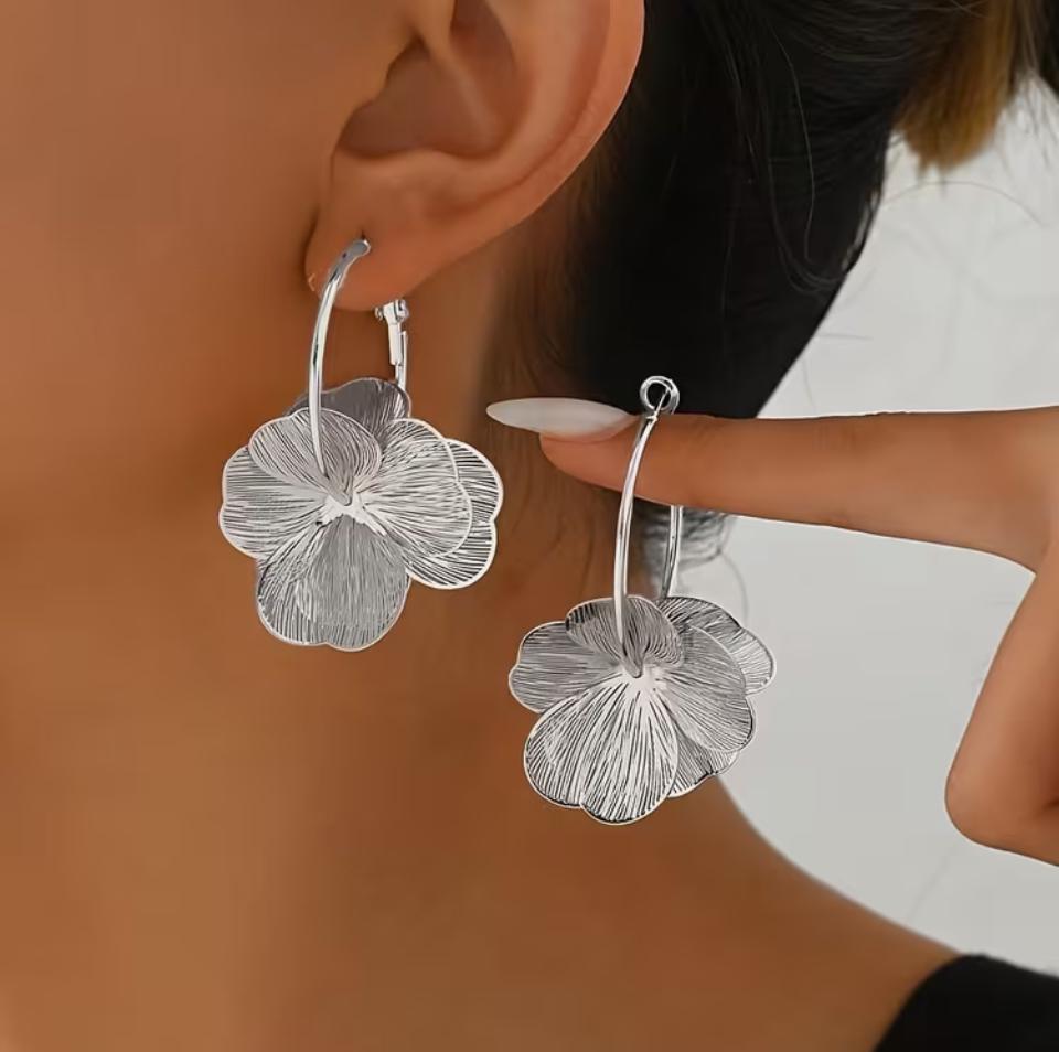 Model feminin purtand cerceii mari de tip tortita cu floare argintie, evidentiind proportiile statement de 5.2 cm si asezarea eleganta pe lob