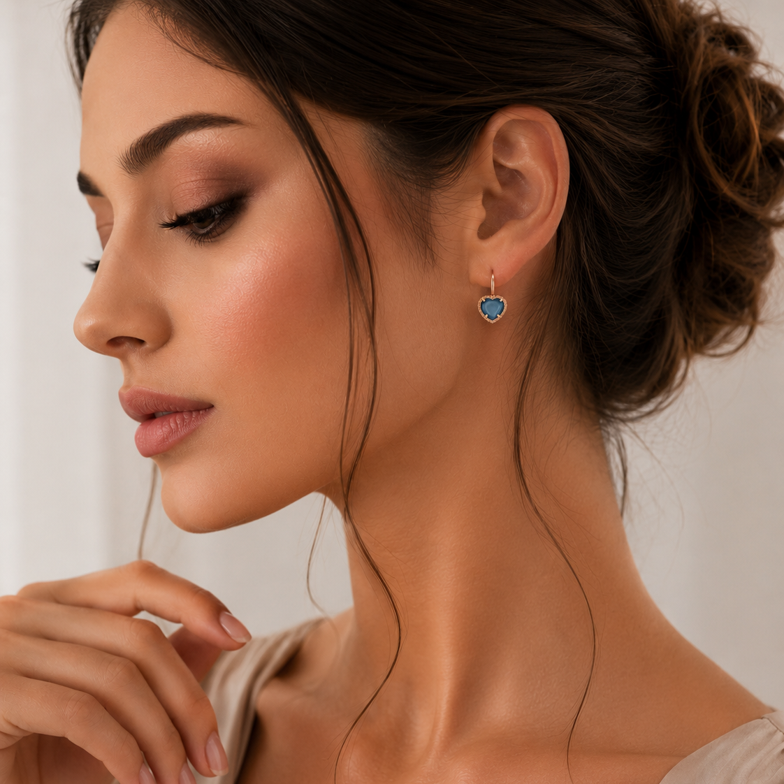 Detaliu cu un model feminin purtand cerceii inima din argint rose gold cu lungimea de 1.5 cm evidentiind reflexiile albastru-indigo ale pietrei.