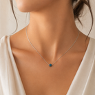  Detaliu la baza gatului cu un model feminin purtand colierul subtire din argint cu pandantiv sferic din cristale swarovski albastre.