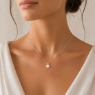 Detaliu la baza gatului cu un model feminin purtand colierul minimalist din argint cu perla de cultura si accent din diamant cz alb.