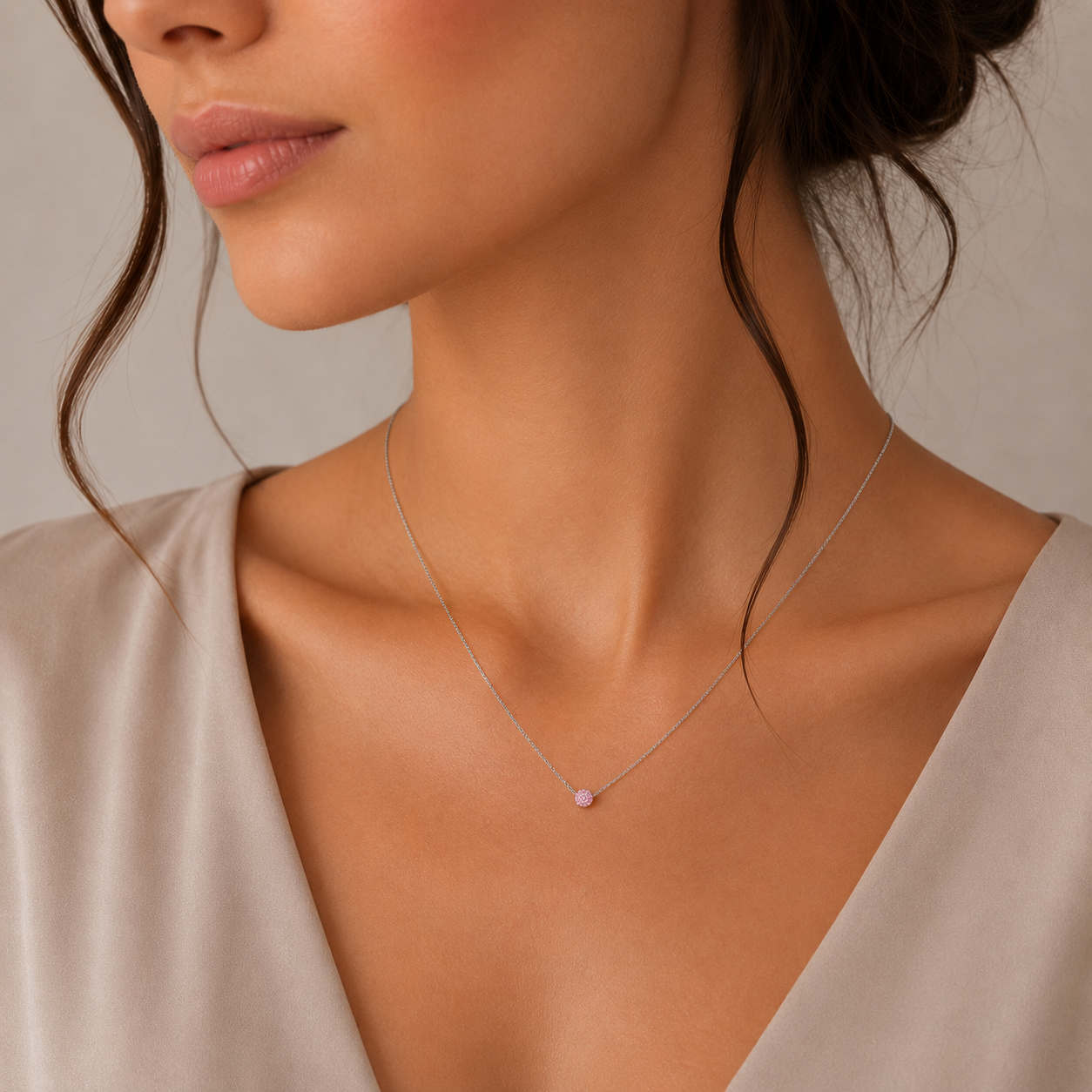 Model feminin purtand colierul fin din argint rodiat cu pandantiv rotund din cristale swarovski roz la baza gatului.
