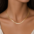  Detaliu la baza gatului cu un model feminin purtand varianta aurie a colierului plat tip sarpe herringbone, cu reflexii calde si stralucitoare