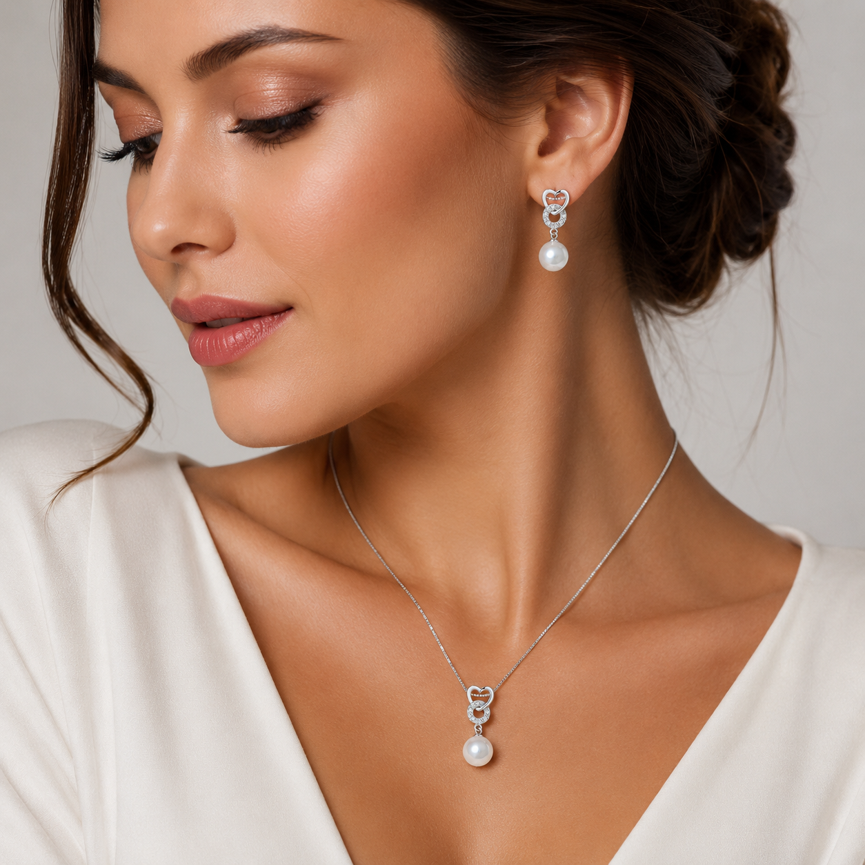 Set complet format din colier si cercei din argint 925 cu pandantiv inima, cerc cu diamante CZ si perla sidef alba, purtat de un model feminin elegant
